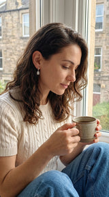 Model wearing gold crystal drop earrings with a sleek ponytail for a soft, polished look