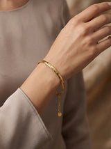 Gold herringbone bracelet styled on the wrist in a warm-toned model shot